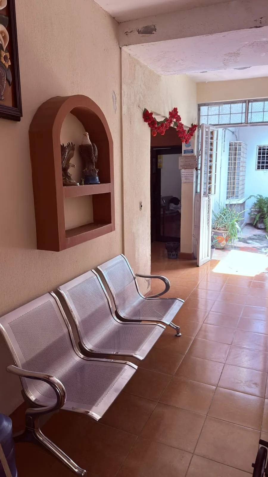 Sala de espera del consultorio con bancas para pacientes y acceso al interior